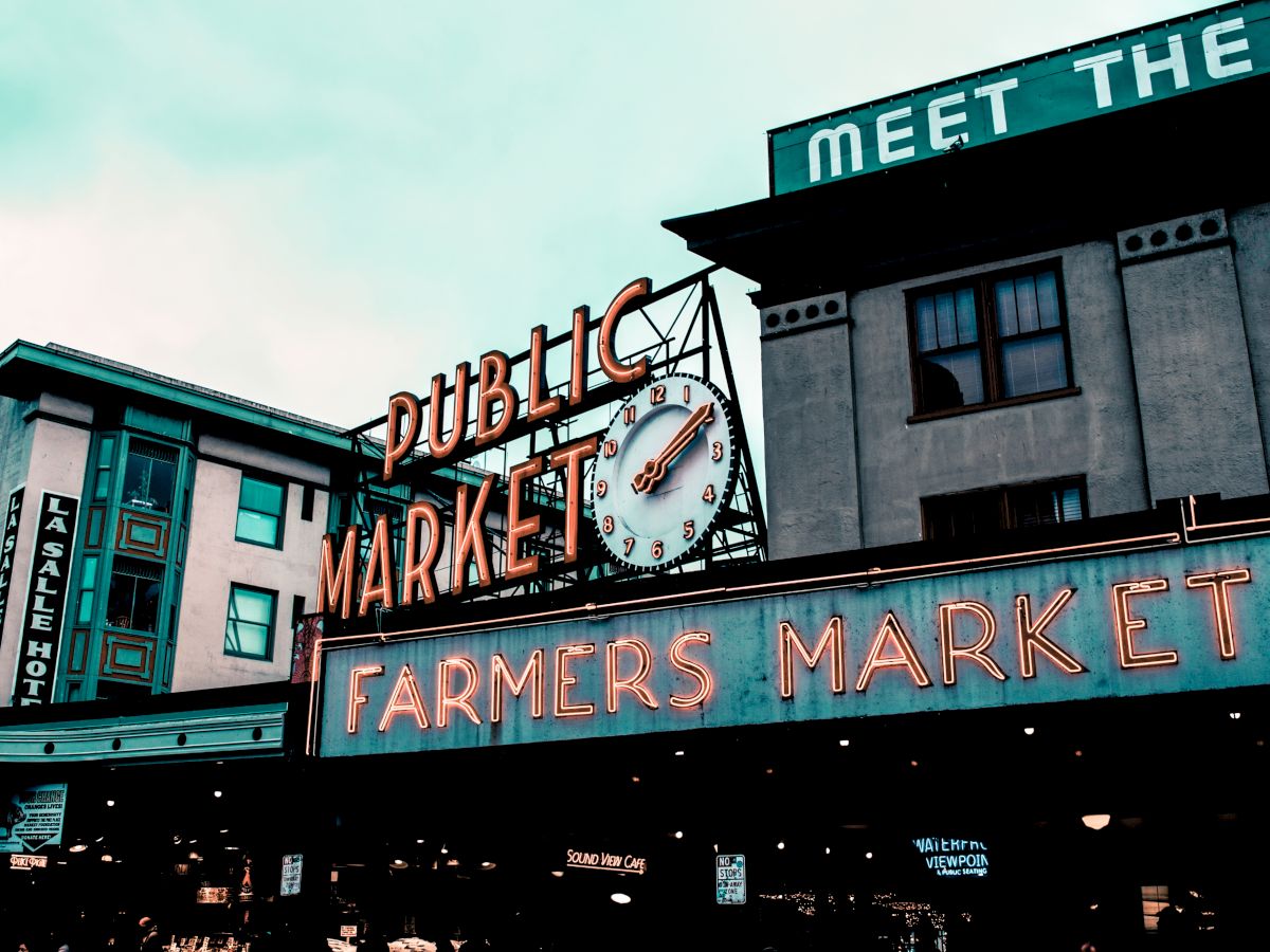 A neon sign reading "Public Market" and "Farmers Market" is prominently displayed, with buildings in the background.